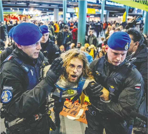  ?? ROBIN UTRECHT / ANP / AFP VIA GETTY IMAGES ?? Royal Dutch police officers escort a Greenpeace activist during a protest to denounce airline pollution in the main hall of the Amsterdam Schiphol airport. The Supreme Court in the Netherland­s has ordered the government to sharply reduce that country’s greenhouse-gas emissions.