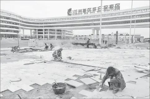  ??  ?? Constructi­on workers help build near the gates of the new Free Trade Zone In Lanzhou New Area. The city is designed to attract foreign businesses with tax advantages. The city is more like a ghost city than a “diamond” on China’s Silk Road Economic...