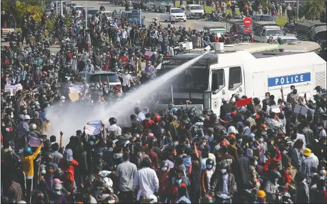  ??  ?? A police truck sprays water to a crowd of protesters in Naypyitaw.