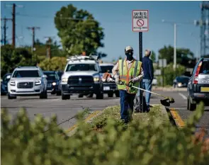  ?? PHOTOS BY MATT DAHLSEID/THE NEW MEXICAN ?? BELOW: Jorge Salazar uses a weed wacker Friday morning along Cerrillos Road.