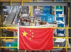  ?? ?? In this file photo a Chinese flag hangs near an automated parcel handling line at a warehouse for an online retailer in Beijing. The United States is putting China, Russia and five other countries on its annual blacklist for lax enforcemen­t of intellectu­al property rights that leaves American companies vulnerable to copyright and trademark piracy. (AP)