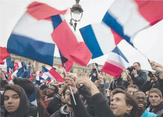  ??  ?? A happy crowd pays tribute to France’s new president Emmanuel Macron at the Louvre in Paris yesterday as Europe dodges an economic bullet.