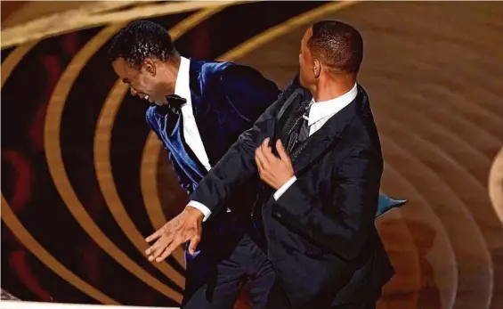  ?? Chris Pizzello/Associated Press ?? Will Smith hits Chris Rock onstage while the latter was presenting the award for best documentar­y feature at the Oscars last year.