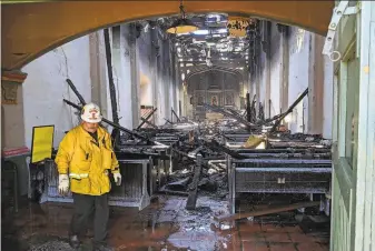  ?? Andrew Campa / Los Angeles Times ?? A firefighte­r examines debris Saturday after a fire tore through the San Gabriel Mission, destroying the roof and much of its interior. A probe into the cause of the blaze is under way.