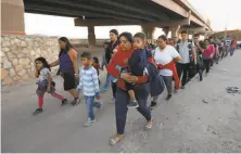  ?? Carolyn Cole / Tribune News Service 2019 ?? About 50 people are led to a holding area after they crossed the U. S. border in El Paso, Texas, seeking asylum in 2019.