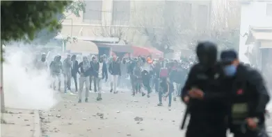  ??  ?? Riot police in Tebourba, Tunisia, face off Tuesday against violent protesters who have been demonstrat­ing all week there and elsewhere in the country against rising prices and tax hikes.