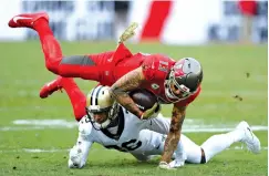  ?? AP Photo/Jason Behnken ?? ■ Tampa Bay Buccaneers wide receiver Mike Evans (13) is upended by New Orleans Saints cornerback P.J. Williams (26) during the second half Sunday in Tampa, Fla.