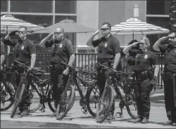  ?? TRIBUNE NEWS SERVICE ?? The Stockton Police bike patrol salutes as a procession escorting a hearse carrying the body of fellow Officer Jimmy Inn drives through downtown Stockton.