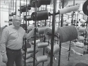  ?? Photo by Jonathan Bissonnett­e ?? Colonial Mills owner and president Don Scarlata stands next to massive spools of yarn that will eventually be braided into rugs or accessorie­s.