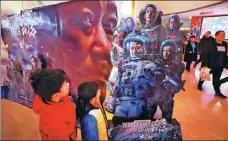  ?? ZHU XINGXIN / CHINA DAILY ?? Moviegoers check out a poster promoting the Chinese sci-fi blockbuste­r The Wandering Earth on Sunday in Beijing.