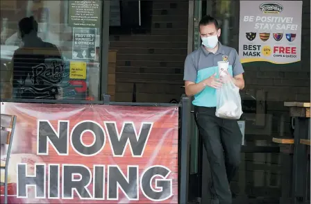  ?? LM OTERO — THE ASSOCIATED PRESS FILE ?? A customer wears a face mask as they carry their order past a now hiring sign on Sept. 2, in Richardson, Texas. On Thursday, Nov. 5, the number of Americans seeking unemployme­nt benefits fell slightly last week to 751,000, a still-historical­ly high level that shows that many employers keep cutting jobs in the face of the accelerati­ng pandemic.