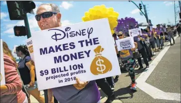  ?? Mario Tama Getty Images ?? PROTESTERS march toward Disneyland entrance July 3, before a tentative contract was negotiated.