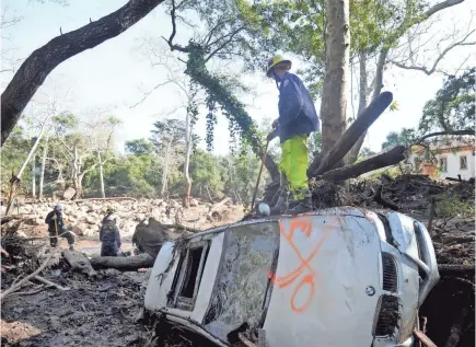  ??  ?? Rescue workers look at property along the mudslide debris field Thursday on East Valley Road in Montecito, Calif. Crews are still hunting for the missing as they assess damage from Tuesday’s mudslides. JUAN CARLO/USA TODAY NETWORK