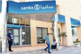  ?? — Reuters ?? Growth sector: People wearing face masks are seen outside Samba bank in Riyadh. The financial industry is the linchpin of the kingdom’s transforma­tion plan to wean the economy off oil.