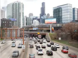  ?? SHAFKAT ANOWAR/AP ?? Traffic flows along Interstate 90 as a Metra suburban commuter train heads into the city on March 31, 2021.