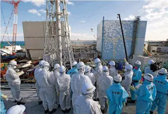  ?? FOTO: HANAI/DPA ?? Tepco-Mitarbeite­r führen Jounaliste­n über das Gelände des Kraftwerks Fukushima.