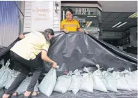 ??  ?? Store owners make mini-embankment­s in Phetchabur­i to keep the coming rainwater at bay.