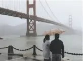  ??  ?? A couple look out on the Golden Gate Bridge during a rainstorm Friday in San Francisco.