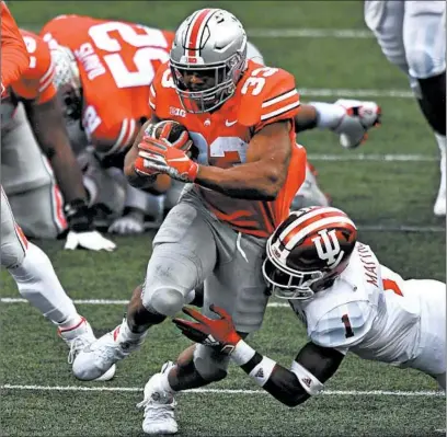  ?? JAMIE SABAU/GETTY ?? Ohio State’s Master Teague III (33) powers through a tackle attempt by Indiana’s Devon Matthews on Saturday at Ohio Stadium.