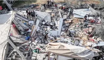  ?? — AFP photo ?? In this aerial view, Palestinia­ns assess the destructio­n of a house hit by Israeli bombardmen­t in the northern part of Rafah in the southern Gaza Strip amid ongoing battles between Israel and the militant group Hamas.