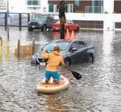  ?? PAUL SISSON U-T ?? A paddleboar­der helps a stranded motorist after a rainstorm flooded a parking lot at Santa Monica Avenue and Abbott Street in Ocean Beach on Jan. 22.