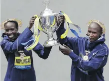  ??  ?? Edna Kiplagat, left, and Geoffrey Kirui, both of Kenya, raise a trophy together after their victories in the 121st Boston Marathon on Monday.
