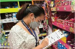  ?? ?? PRICE MONITORING. A Department of Trade and Industry (DTI) staff checks on the prices of commoditie­s at a grocery store in Dumaguete City in this Dec. 21, 2021 photo.