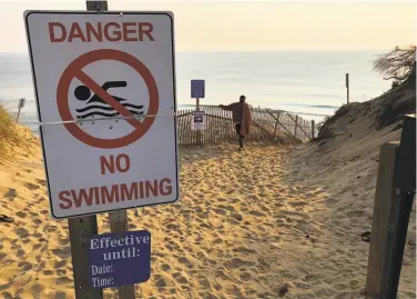  ?? William J. Kole / Associated Press ?? A sign prohibits swimming at the beach in Truro in August after a man was attacked there by a shark.