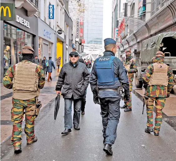  ?? AP ?? Tensión. Un hombre camina en una calle de Bruselas frente a un camión militar y entre soldados y policías, la escena de una ciudad en peligro.