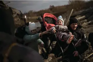  ?? The Associated Press ?? ■ A child is carried on a stroller across an improvised path on March 9, 2022, while fleeing Irpin, on the outskirts of Kyiv, Ukraine.
