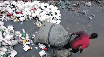  ?? PICTURE: DIEU NALIO CHERY / AP ?? DOWNTRODDE­N: A man pulls his bag through a littered water canal in downtown Port-au-Prince, Haiti. Scientists say cholera was introduced to the country’s biggest river by Nepalese peacekeepe­rs.