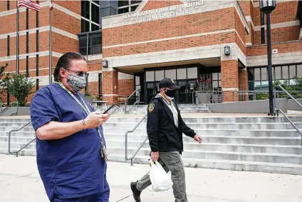  ?? Tom Reel / Staff photograph­er ?? Personnel leave the Sheriff ’s Office and Detention Center. As of Sunday, 20 inmates have been infected with the coronavius.