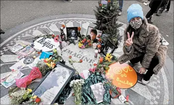  ?? TIMOTHY A. CLARY/GETTY-AFP ?? Rememberin­g John Lennon: A woman makes a peace sign Tuesday at Strawberry Fields in New York’s Central Park while marking the 40th anniversar­y of John Lennon’s death. On Dec. 8, 1980, the ex-Beatle was with his wife, Yoko Ono, when he was shot outside his Manhattan apartment by Mark David Chapman. He was again denied parole in August.