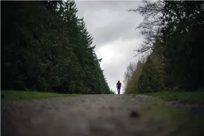  ?? The Associated Press ?? ■ Nathan Lambrecht, walks along a trail he used to frequent with his father, Doug Lambrecht, on March 21 in Woodinvill­e, Wash. Doug Lambrecht was among the first of the nearly 1 million Americans to die from COVID-19. With 1 million deaths in sight, his son reflected on the toll. “I’m afraid that as the numbers get bigger, people are going to care less and less,” he said. “I just hope people who didn’t know them and didn’t have the same sort of loss in their lives due to COVID, I just hope that they don’t forget and they remember to care.”