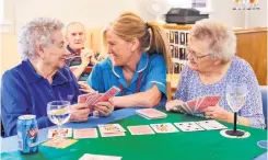  ?? ?? Fun Residents Ina Franklin and Maisie Bradley playing cards with activities assistant Carole Little