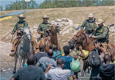  ?? FELIX MARQUEZ/ASSOCIATED PRESS ?? Mounted officers with U.S. Customs and Border Protection attempt to contain migrants Sunday as they cross the Rio Grande from Ciudad Acuña, Mexico, into Del Rio, Texas. Thousands of Haitian migrants have been arriving in Del Rio as authoritie­s attempt to close the border and stop the flow.