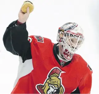  ??  SEAN KILPATRICK/THE CANADIAN PRESS ?? Ottawa Senators’ Andrew Hammond, nicknamed ‘The Hamburglar,’ holds up a hamburger after it was thrown on the ice after he defeated the Philadelph­ia Flyers 2-1 on Sunday.