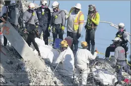  ?? MARK HUMPHREY — THE ASSOCIATED PRESS ?? A team secures sets of recovered remains in body bags as other search and rescue personnel work on top of the rubble at the Champlain Towers South condo building Friday in Surfside, Fla.