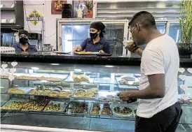  ?? /Reuters ?? Slice of the pie: A customer eats a pastry at a bakery, in Caracas, Venezuela. The economy has benefited from dollarisat­ion, which has helped imports of ingredient­s such as wheat flour.