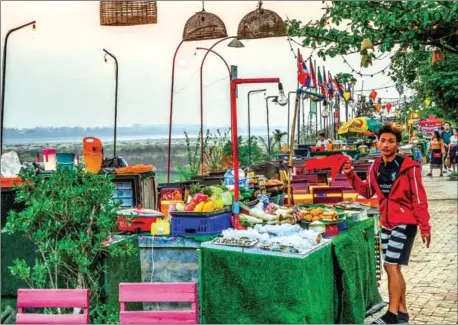  ?? AFP ?? An employee invites customers at an open air restaurant on the banks of the Mekong river in Vientiane. The resumption of business is not a cause for celebratio­n, but a time of great challenge for operators in the wake of their closure during the lockdown.