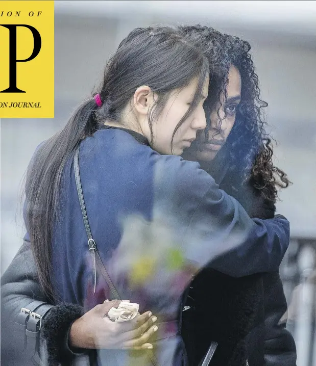  ?? PETER J THOMPSON / NATIONAL POST ?? Two women embrace on Yonge Street in Toronto Tuesday next to a makeshift memorial to those killed and injured in Monday’s bloody van attack. Alek Minassian was charged with 10 counts of first-degree murder and 13 counts of attempted murder in Toronto court on Tuesday.