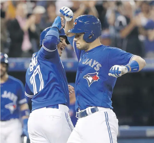  ?? — GETTY IMAGES ?? Ryan Goins, left, congratula­tes teammate Luke Maile after the backup catcher cracked a two-run homer in the fifth inning of Toronto’s 5-4 win over the Cincinnati Reds on Wednesday. Maile entered the contest with just three hits in 52 trips to the plate.