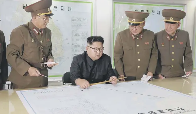  ?? PICTURE: AFP/GETTY IMAGES ?? 0 North Korean leader Kim Jong Un looks over the plans drawn up by his military for a missile strike in the vicinity of Guam