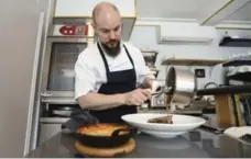  ?? ?? Chef Doug Penfold plates a lamb shoulder in the tiny open kitchen area.