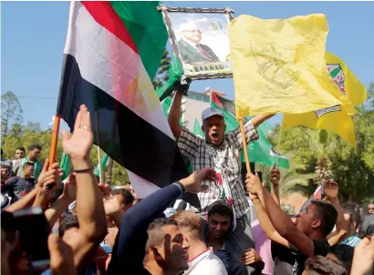  ?? AFP ?? Men wave Palestinia­n and Fatah party flags as they celebrate in Gaza City after rival Palestinia­n factions Hamas and Fatah reached an agreement on ending a decade-long split following talks mediated by Egypt on Thursday. —