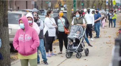  ?? ANTHONYVAZ­QUEZ/SUN-TIMES ?? Residents wait in line outside a COVID-19 testing site in Little Village earlier this month.