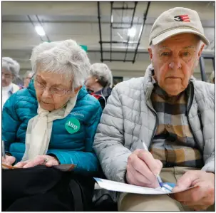  ?? (AP/Charlie Neibergall) ?? Lenora and Norman Iverson fill out their presidenti­al preference cards during a Democratic caucus Monday at Hoover High School in Des Moines. More photos at arkansason­line.com/24iowa/.