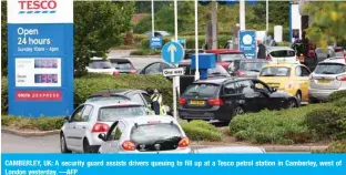  ?? ?? CAMBERLEY, UK: A security guard assists drivers queuing to fill up at a Tesco petrol station in Camberley, west of London yesterday. —AFP