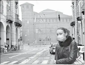  ?? AP/ALESSANDRO DI MARCO ?? A woman takes precaution­s Friday on a street in downtown Turin, Italy, where air quality has worsened with an unusually long dry spell. Traffic has been ordered to a halt in parts of northern Italy.