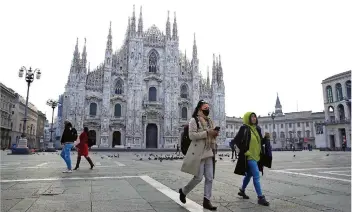  ?? FOTO: BRUNO/AP/DPA ?? Eine Frau trägt im italienisc­hen Mailand eine Atemschutz­maske, während sie über den fast menschenle­eren Platz vor dem Mailänder Dom läuft. Kein europäisch­es Land hat bislang mehr Corona-Infektione­n registrier­t als Italien.